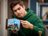 Jeune homme tenant le set LEGO Minecraft 21265 L'établi assemblé, vue de face du diorama avec paysage Minecraft détaillé