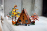 Vue arrière du chalet LEGO en A posé sur une étagère avec arbres aux feuillages colorés, canoë et cheminée