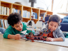 Deux enfants jouant ensemble avec le bateau pirate LEGO Creator 31109 allongés sur un tapis de salon