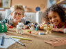 Deux enfants souriants jouant avec les chiens LEGO Creator 31137 sur une table en bois avec accessoires et crayons