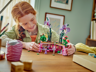 Enfant jouant avec le set LEGO Disney 43237 ouvert sur un bureau en bois, manipulant le pot de fleurs d'Isabela