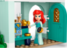 Gros plan sur la mini-poupée LEGO Ariel aux cheveux rouges dans sa boutique d'antiquités avec carte au trésor et objets dorés