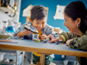 Enfant souriant jouant avec le vaisseau spatial LEGO City 60429 aux côtés de sa mère, scène de jeu parent-enfant