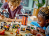 Enfants souriants explorant l'intérieur de la base spatiale LEGO City 60434 avec minifigurines aliens et astronautes