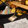 Atelier de peinture à l'aérographe d'une pièce d'armure dorée du Sagittaire avec nuancier Pantone et croquis de conception