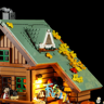 Détail du toit vert du chalet avec lucarne, feuilles automnales jaunes, balcon éclairé et figurines sur la terrasse
