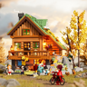 Chalet de montagne en briques éclairé dans un décor naturel automnal avec figurines, vélo et arbre jaune
