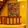 Détail intérieur montrant un tableau style vitrail avec des roses rouges et roses, escalier et balustrade en bois