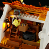 Intérieur du moulin avec minifigurine de meunier tenant une cruche, escalier en bois et lanterne LED allumée