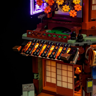 Détail du toit traditionnel japonais en tuiles noires avec éclairage LED ambré et fleurs de cerisier décoratives