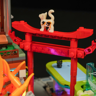 Chat calico perché sur un torii rouge miniature illuminé en violet, détail du set Izakaya F9073