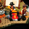 Gros plan des minifigurines cowboy autour du feu de camp LED rouge avec chaudron, guitare et tente en arrière-plan