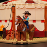 Figurine de cow-boy à cheval brun décoré de motifs western devant le chapiteau du cirque Lumibricks L9079