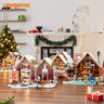 Collection complète de chalets Lumibricks illuminés exposés sur table en bois dans un décor de Noël