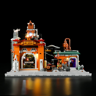 Vue de face de l'usine Ore Factory éclairée sur fond noir, façade orange avec enseigne, toit rouge et laboratoire VoidLab adjacent
