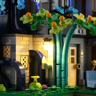 Gros plan sur la lanterne murale éclairée et le petit arbre vert avec fruits oranges devant la façade en pierre